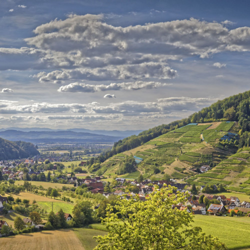 Blick in ein breites Tal mit wolkigem Himmel