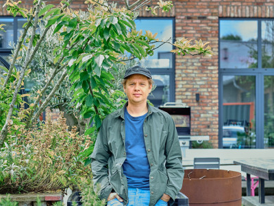 Ein Mann steht in einem bepflanzten Innenhof