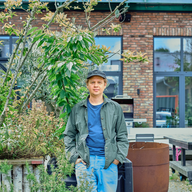 Ein Mann steht in einem bepflanzten Innenhof