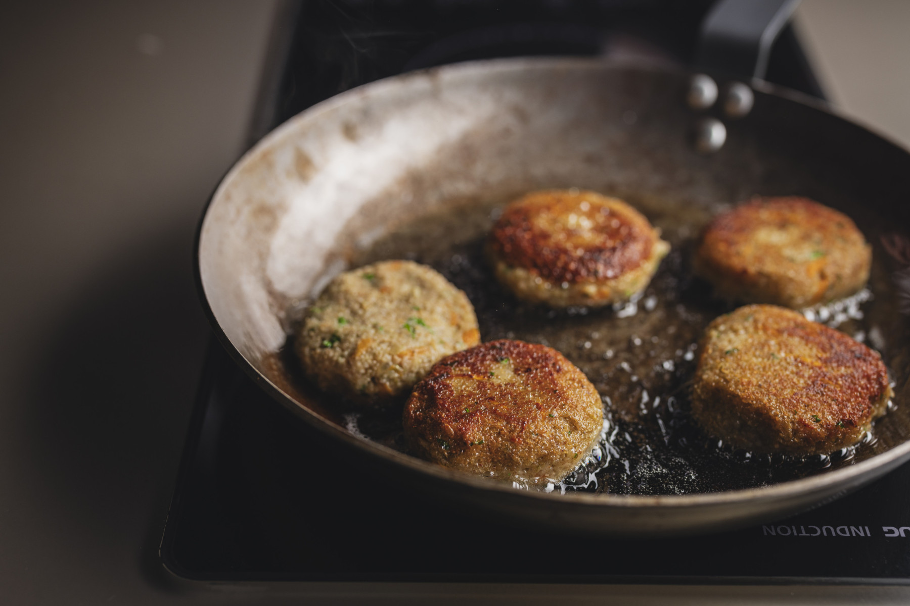 Eine Pfanne mit Öl und gebratenen Grünkern-Bratlingen