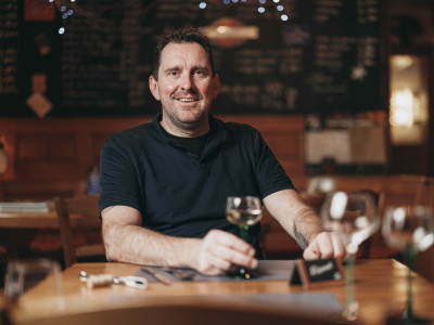 Der Wirt Helmut mit einem Glas Weißwein