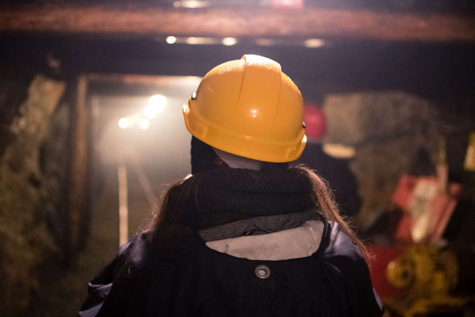 Eine Frau mit gelbem Schutzhelm läuft durch ein Besucherbergwerk.