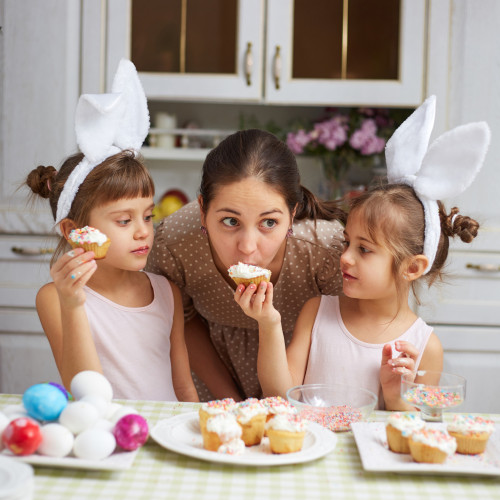 Eine Mutter mit Zwillingen beißt in einem Muffin, den ihr die Tochter hinhält