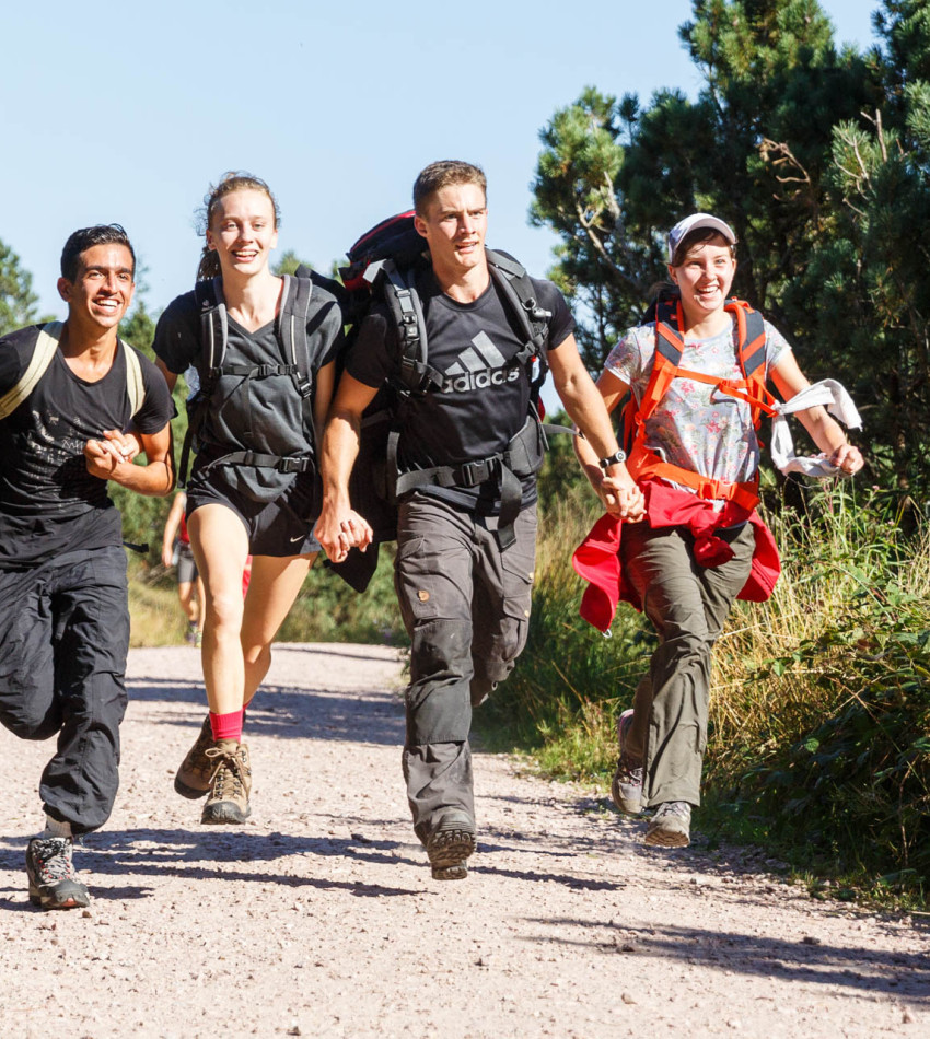 Eine Gruppe Jugendlicher rennt auf einem Weg im Freien.