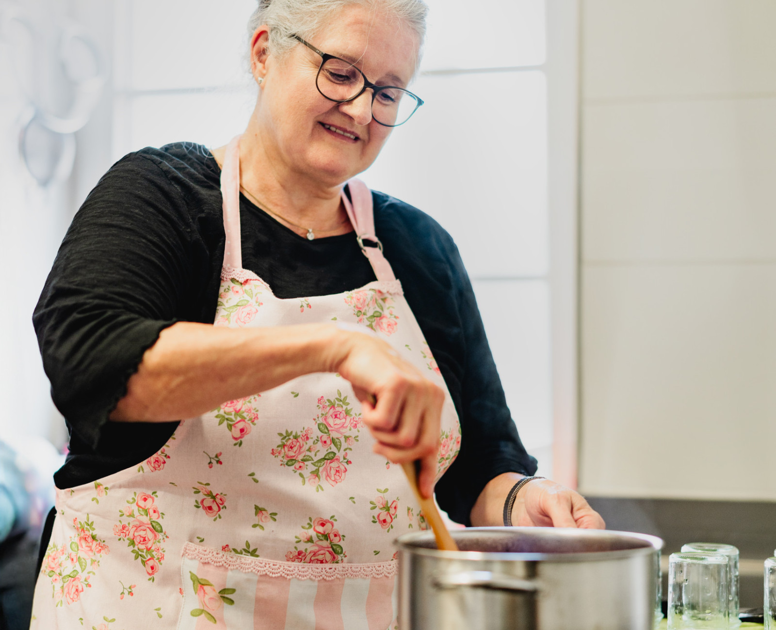 Frau mit Schürze rührt in einem Kochtopf