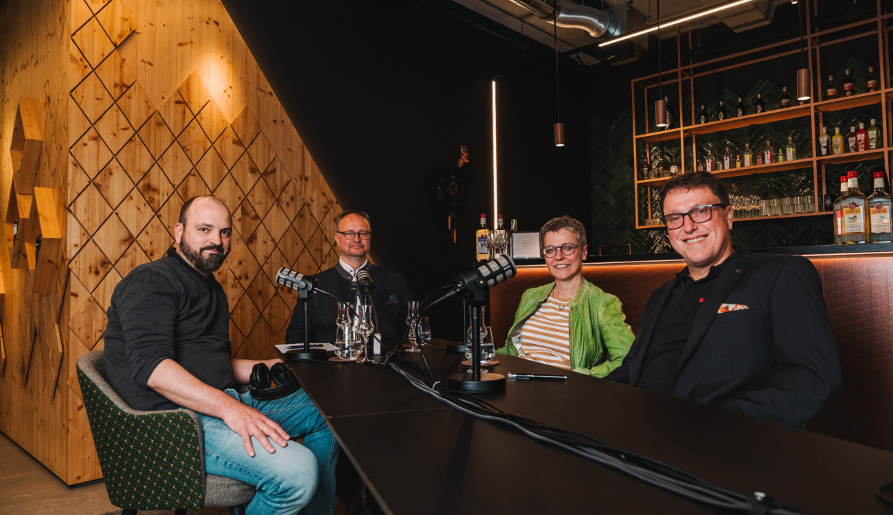 Vier Personen bei Podcast-Aufnahme in moderner Bar-Atmosphäre bei Bimmerle im Schwarzwald, Mikrofone und Gläser auf dem Tisch