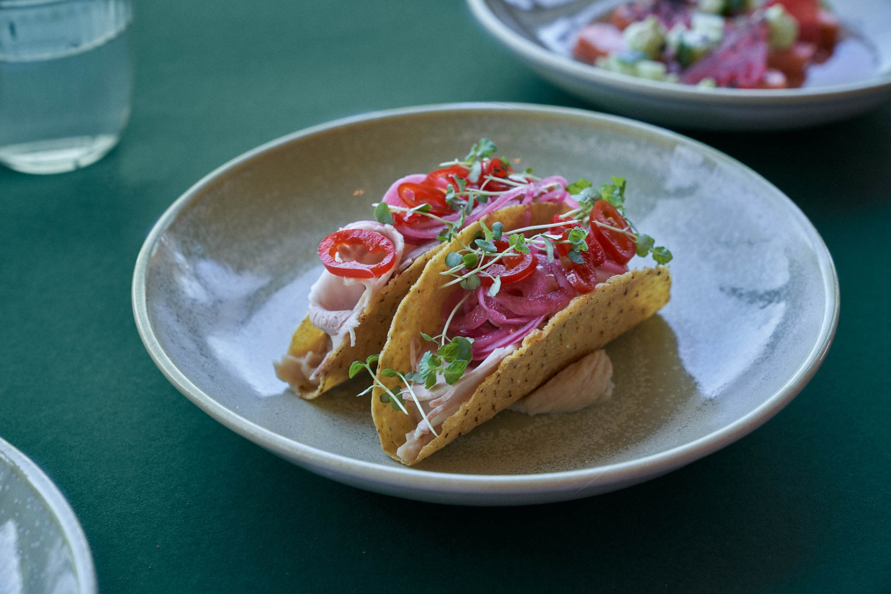 Zwei Tacos mit bunten Zutaten auf einem weißen Teller.