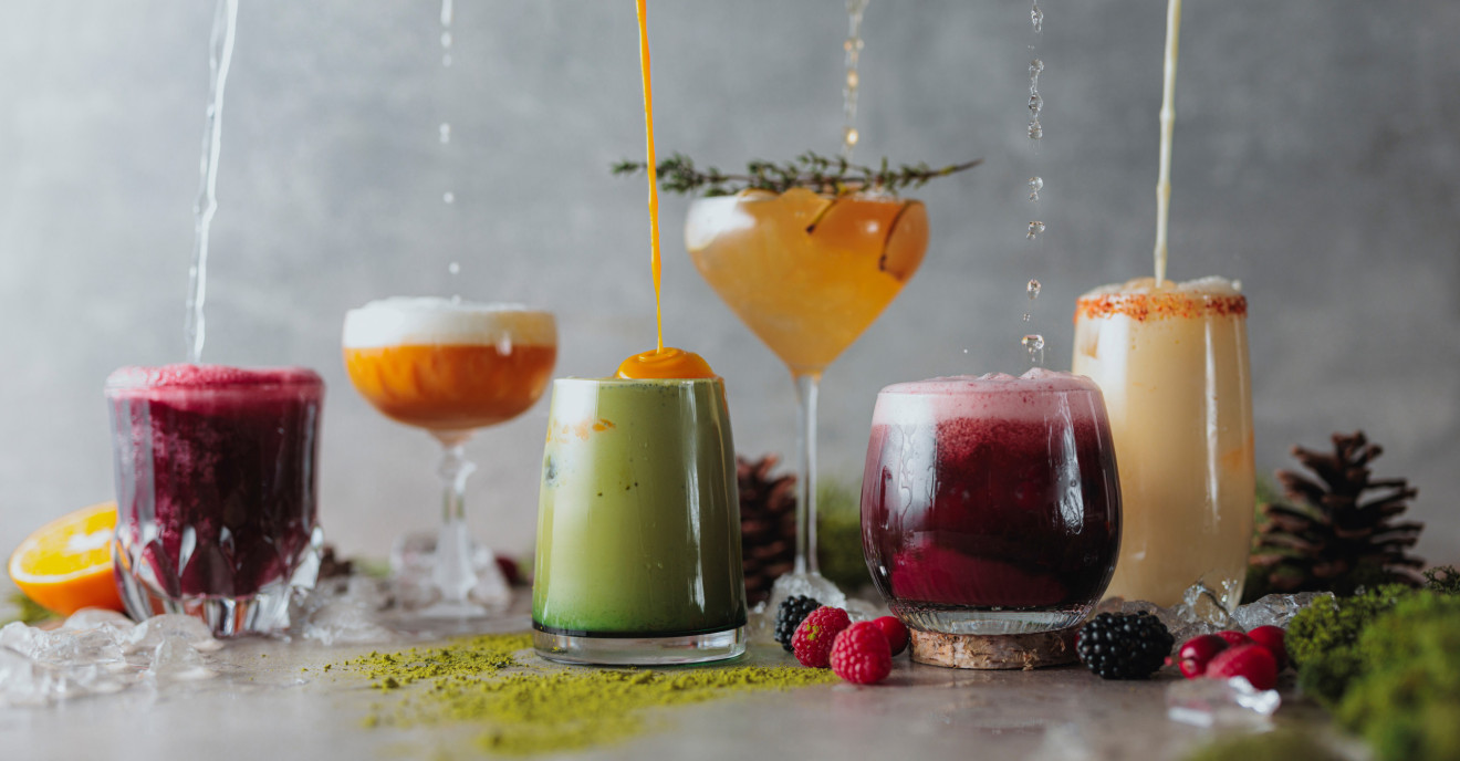 Sechs farbenfrohe Cocktails stehen in einer Reihe