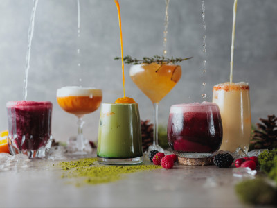 Sechs farbenfrohe Cocktails stehen in einer Reihe