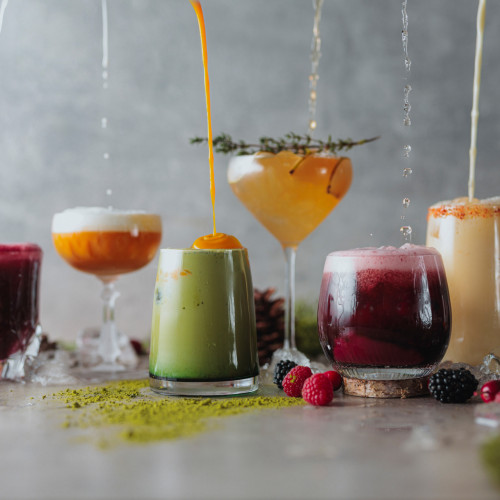 Sechs farbenfrohe Cocktails stehen in einer Reihe