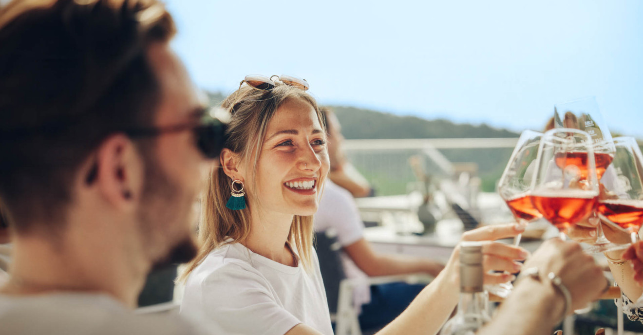 Mehrere junge Menschen stoßen mit Rosé Wein an.