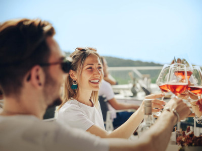 Mehrere junge Menschen stoßen mit Rosé Wein an.