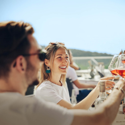 Mehrere junge Menschen stoßen mit Rosé Wein an.