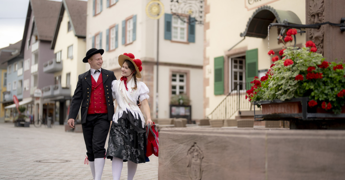 Ein Paar in Schwarzwälder Tracht schlendert Arm in Arm durch die Oberkircher Innenstadt.