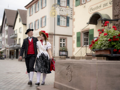 Ein Paar in Schwarzwälder Tracht schlendert Arm in Arm durch die Oberkircher Innenstadt.