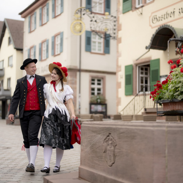 Ein Paar in Schwarzwälder Tracht schlendert Arm in Arm durch die Oberkircher Innenstadt.