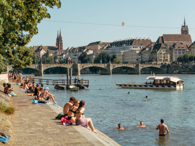 Badende Menschen im Rhein und am Rheinufer in Basel.