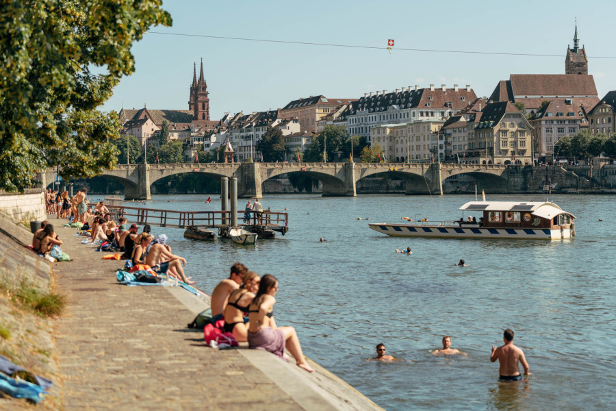 Badende Menschen im Rhein und am Rheinufer in Basel.