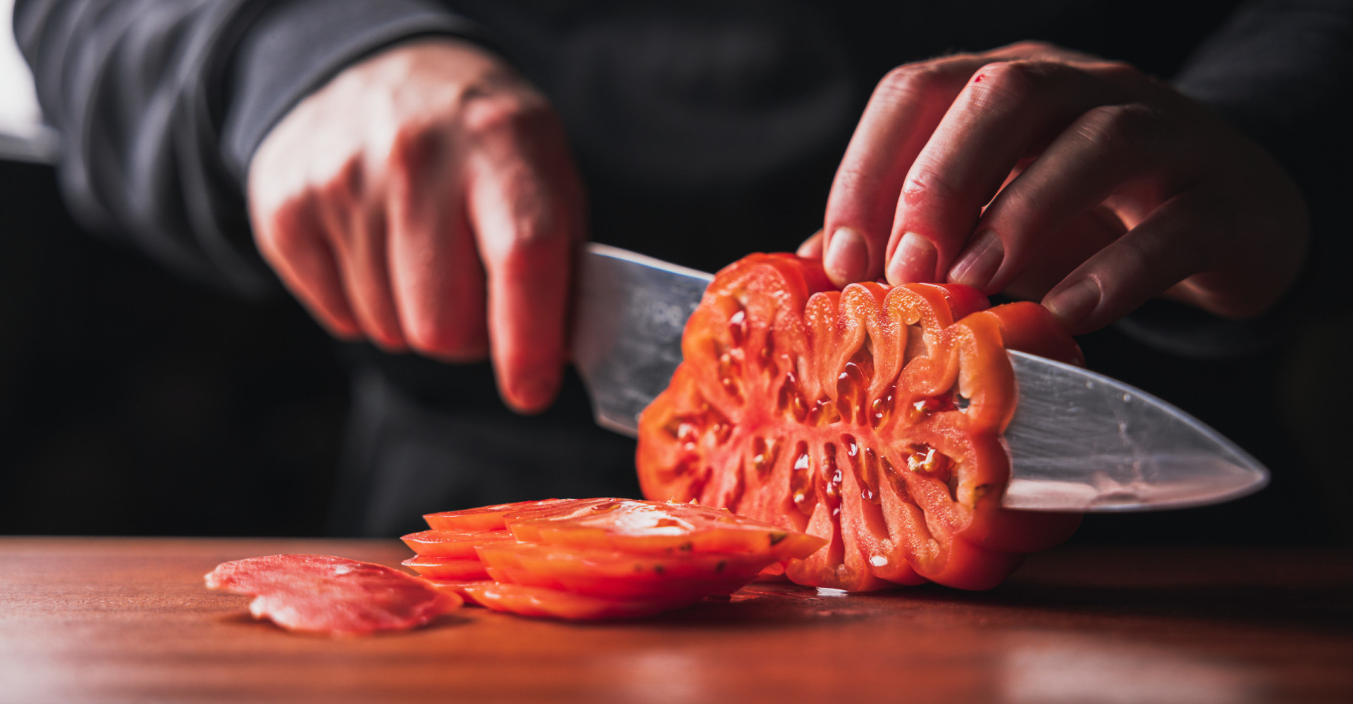 Person schneidet Ochsenherztomate