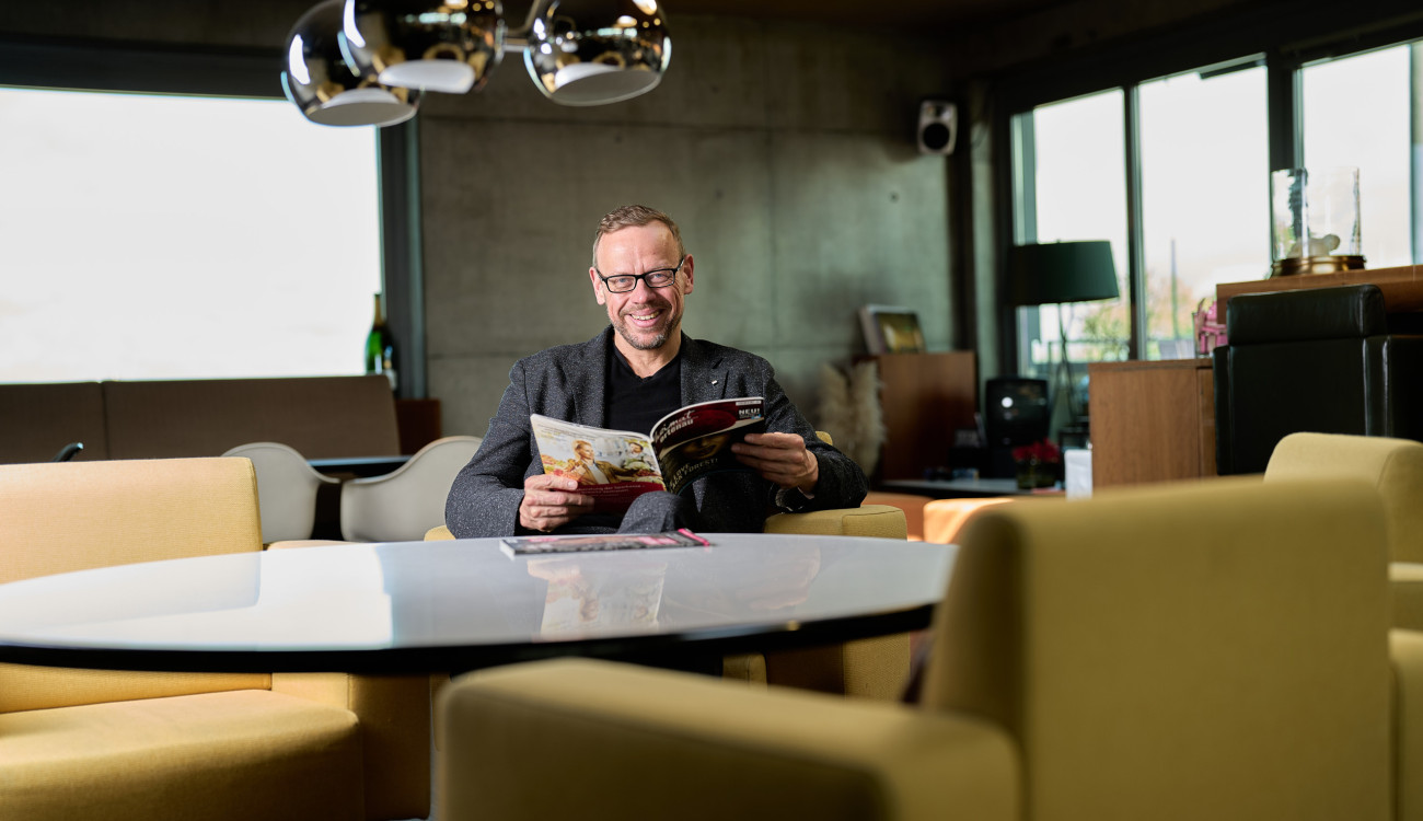 Ulf Tietge sitzt entspannt in moderner Lounge und liest eine Ausgabe des Magazins #heimat schwarzwald