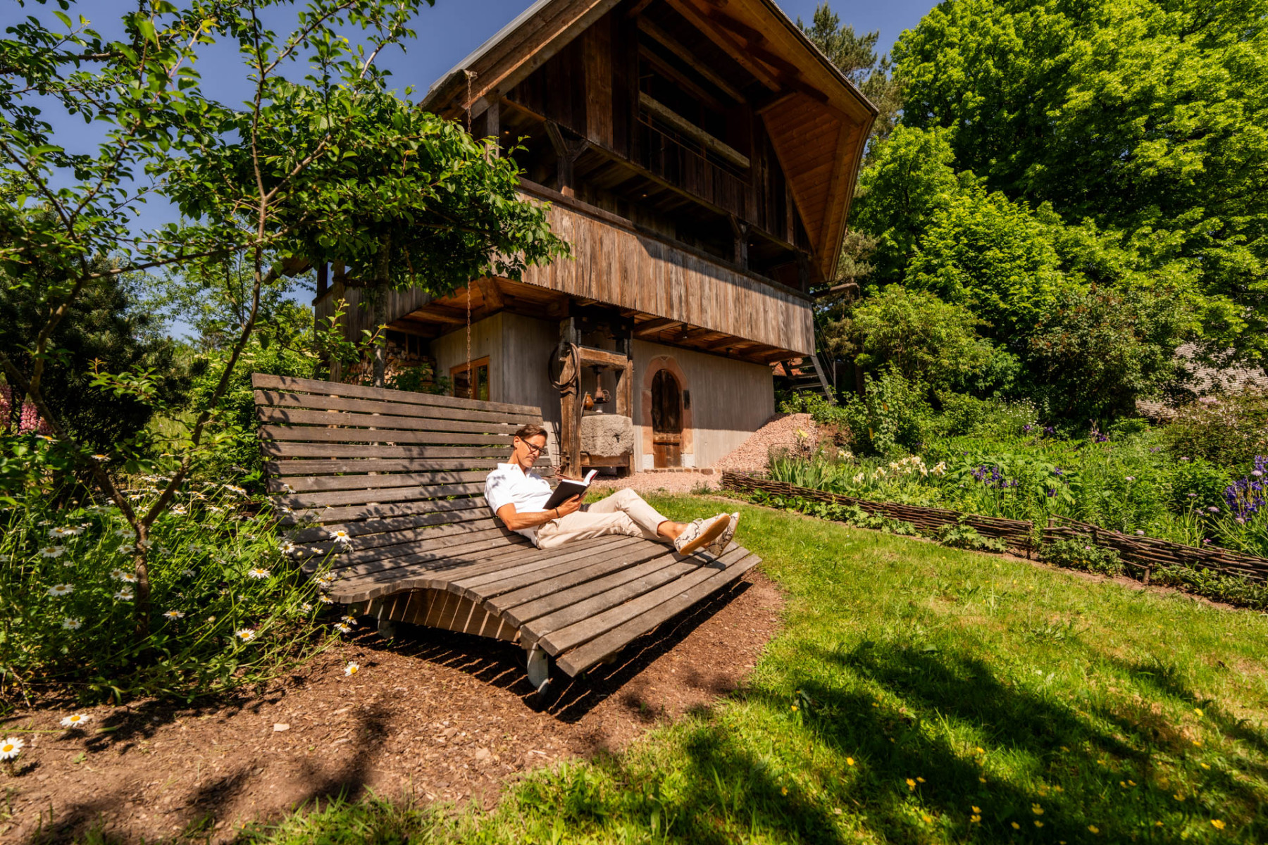 Hardy Happle auf einem Liegestuhl aus Holz im Garten seines Schwarzwaldhauses.