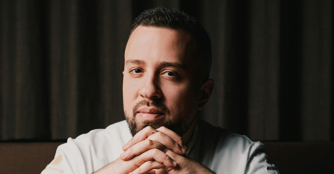 Ein Koch mit Tattoos sitzt an einem Esstisch 