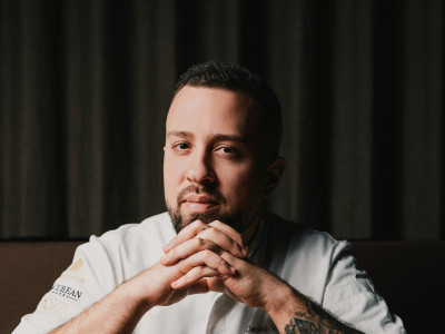 Ein Koch mit Tattoos sitzt an einem Esstisch 