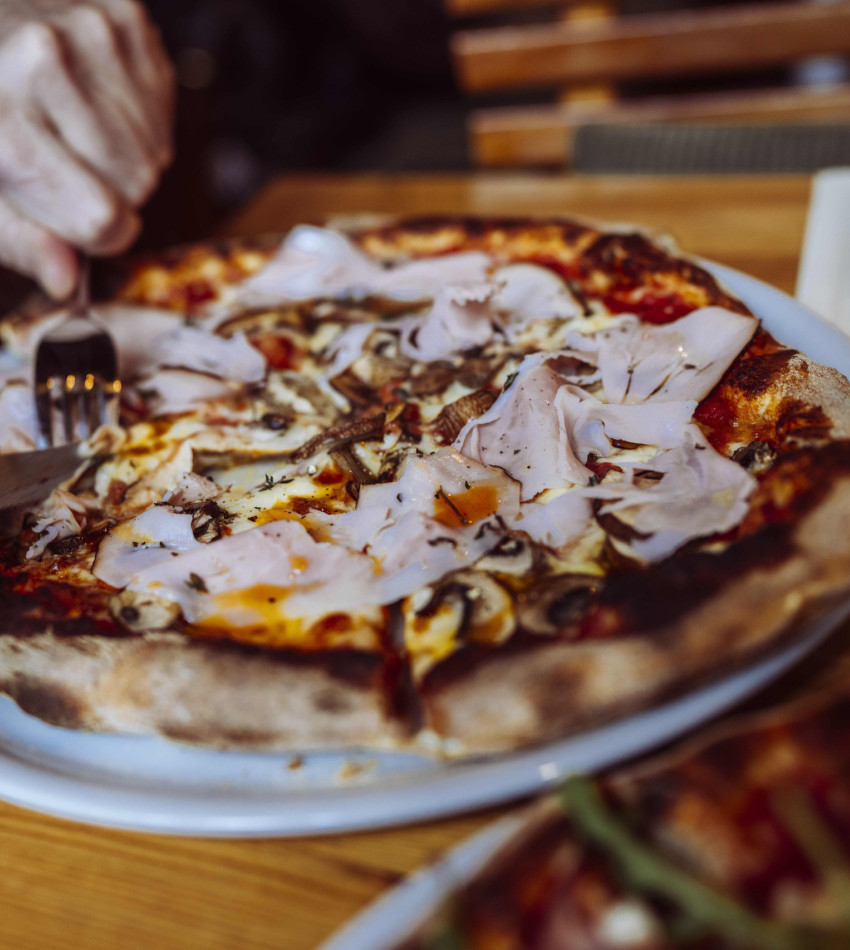 Die Pizza Schinke-Champignons wird gerade geschnitten