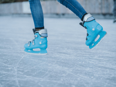 Zwei Füße in Schlittschuhen gleiten über eine Eisbahn