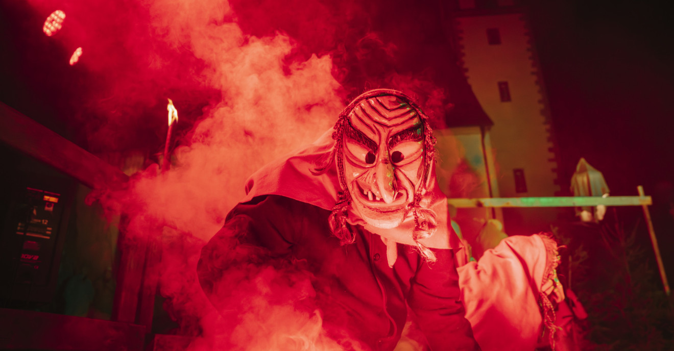 Eine Hexe tanzt zur Fastnacht im Dunkeln auf einer rot beleuchteten Bühne