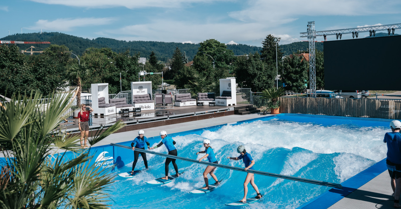 Vier Personen surfen auf einer künstlichen Welle