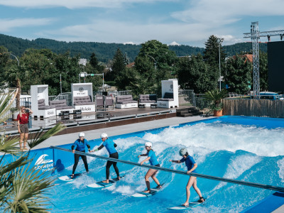 Vier Personen surfen auf einer künstlichen Welle