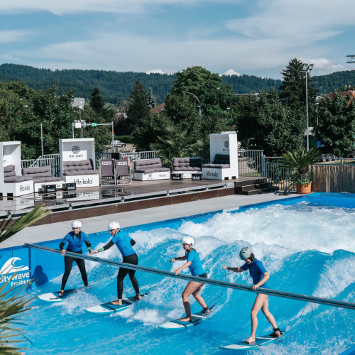 Vier Personen surfen auf einer künstlichen Welle